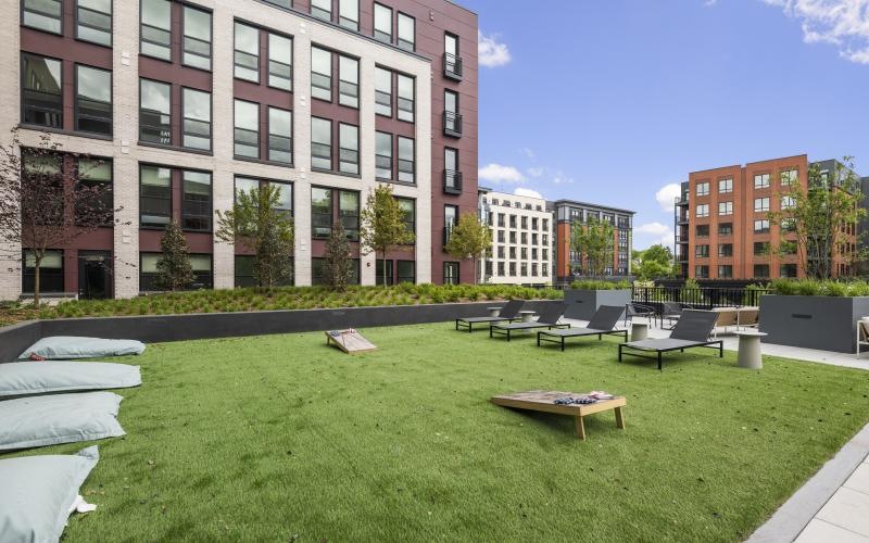 a grassy area with tables and chairs in it and buildings in the background